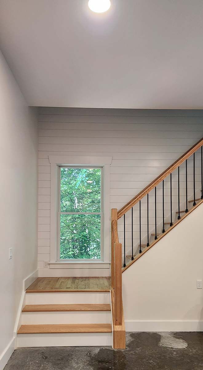 There is a staircase in the middle of a room with a window.