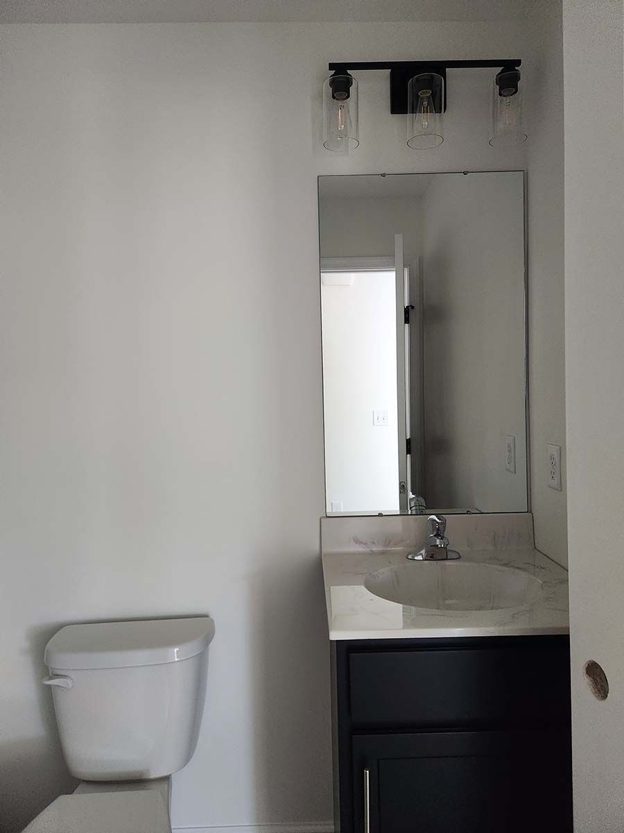 A bathroom with a toilet , sink and mirror.
