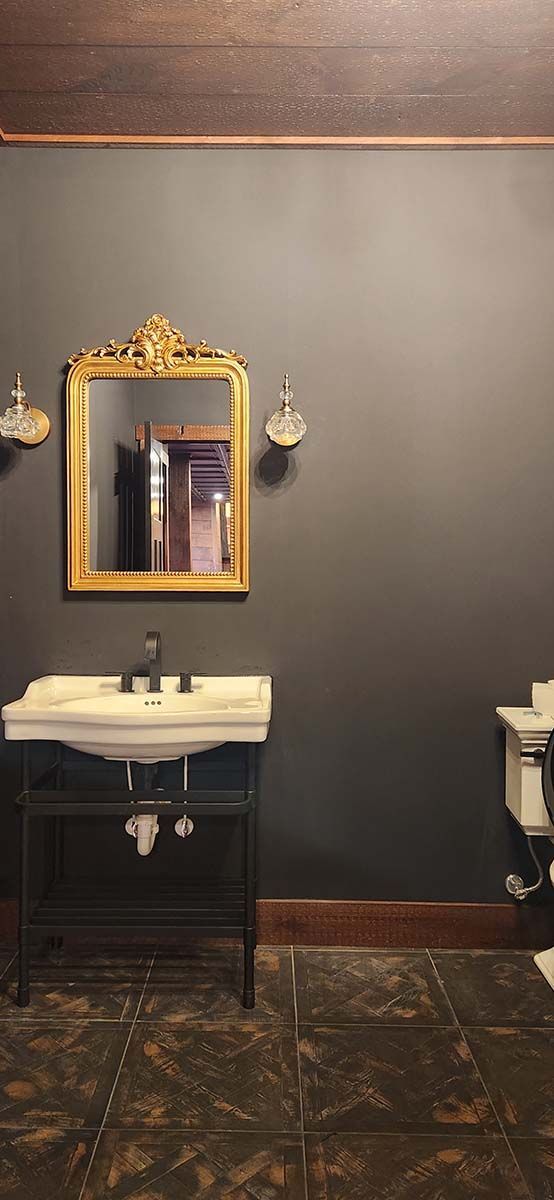 Upscale mancave bathroom with a sink , mirror and toilet.