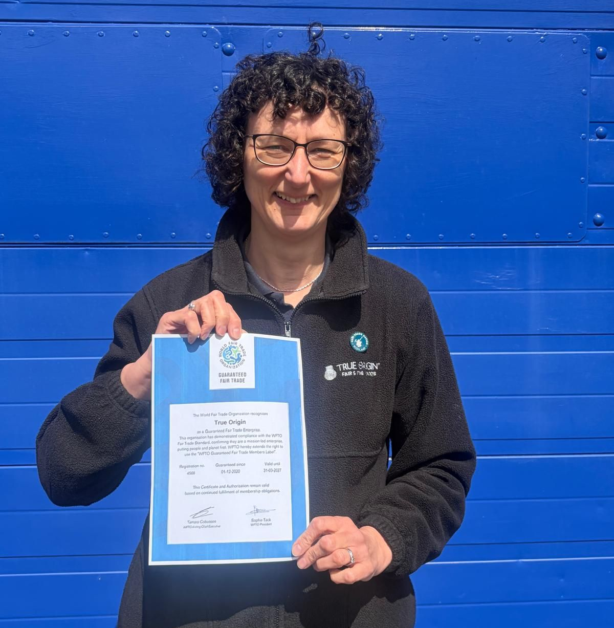 Fair Trade food company True Origin MD, Tracy Mitchel shows off the company's renewed WFTO Guaranteed Member Status certificate