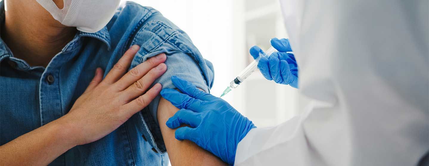 Person receiving a vaccination injection in the arm by a medical professional.