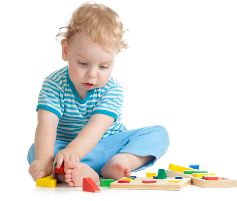 A little boy is sitting on the floor playing with wooden blocks.