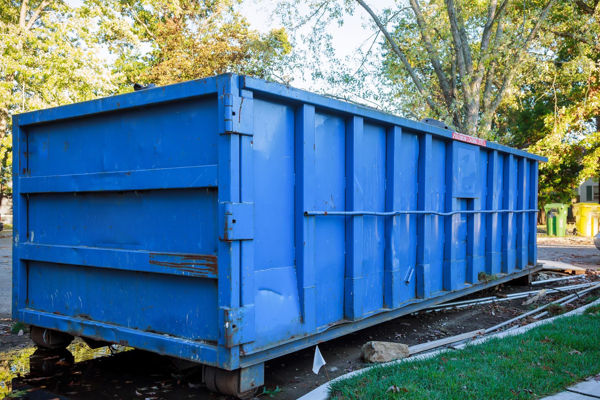 Flatbed trailer parked on grass near trees and a wooded area.