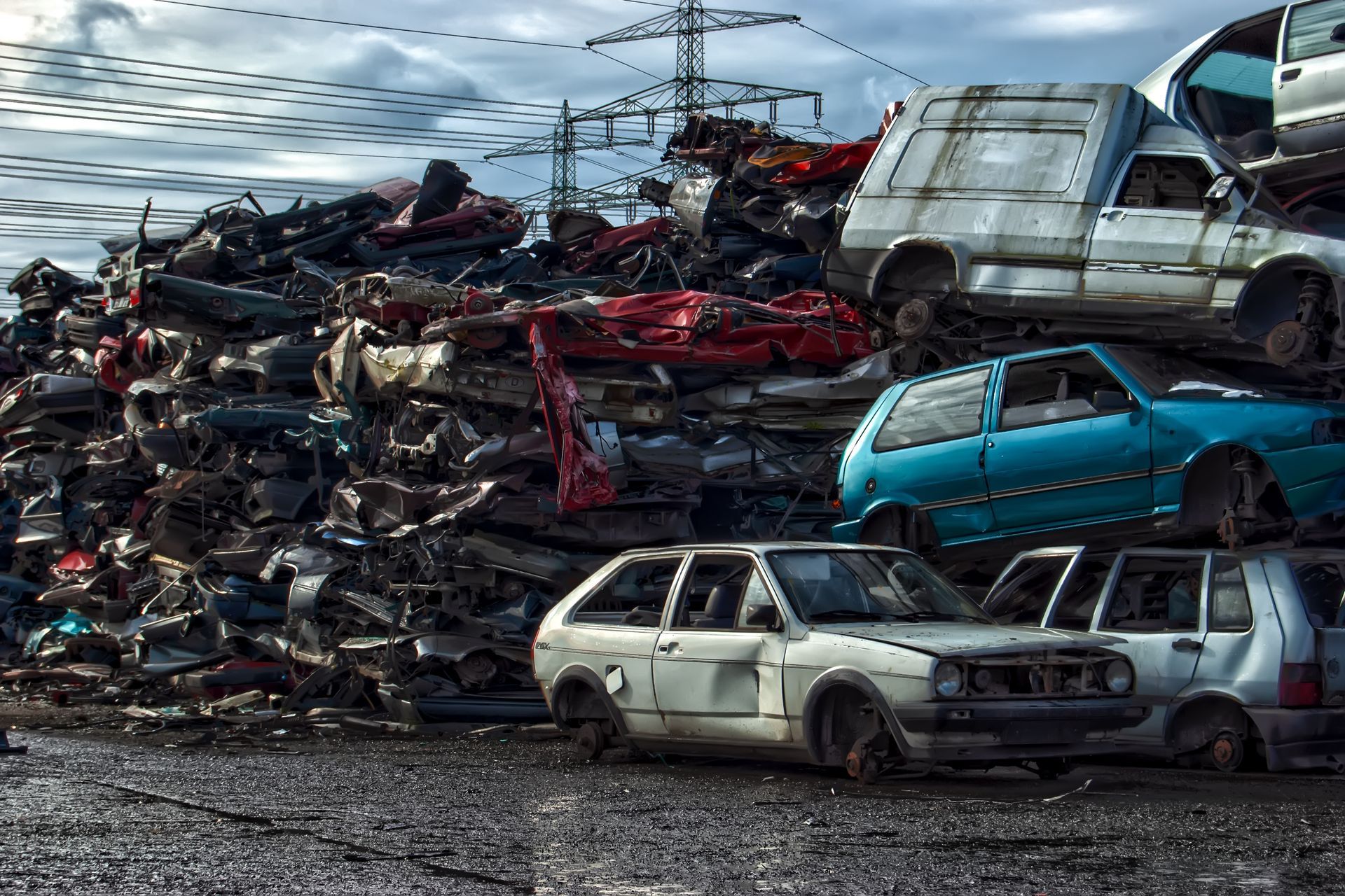 Scrap metal yard filled with wrecked cars, cloudy sky in the background. Scrap metal yard filled with wrecked cars, cloudy sky in the background.