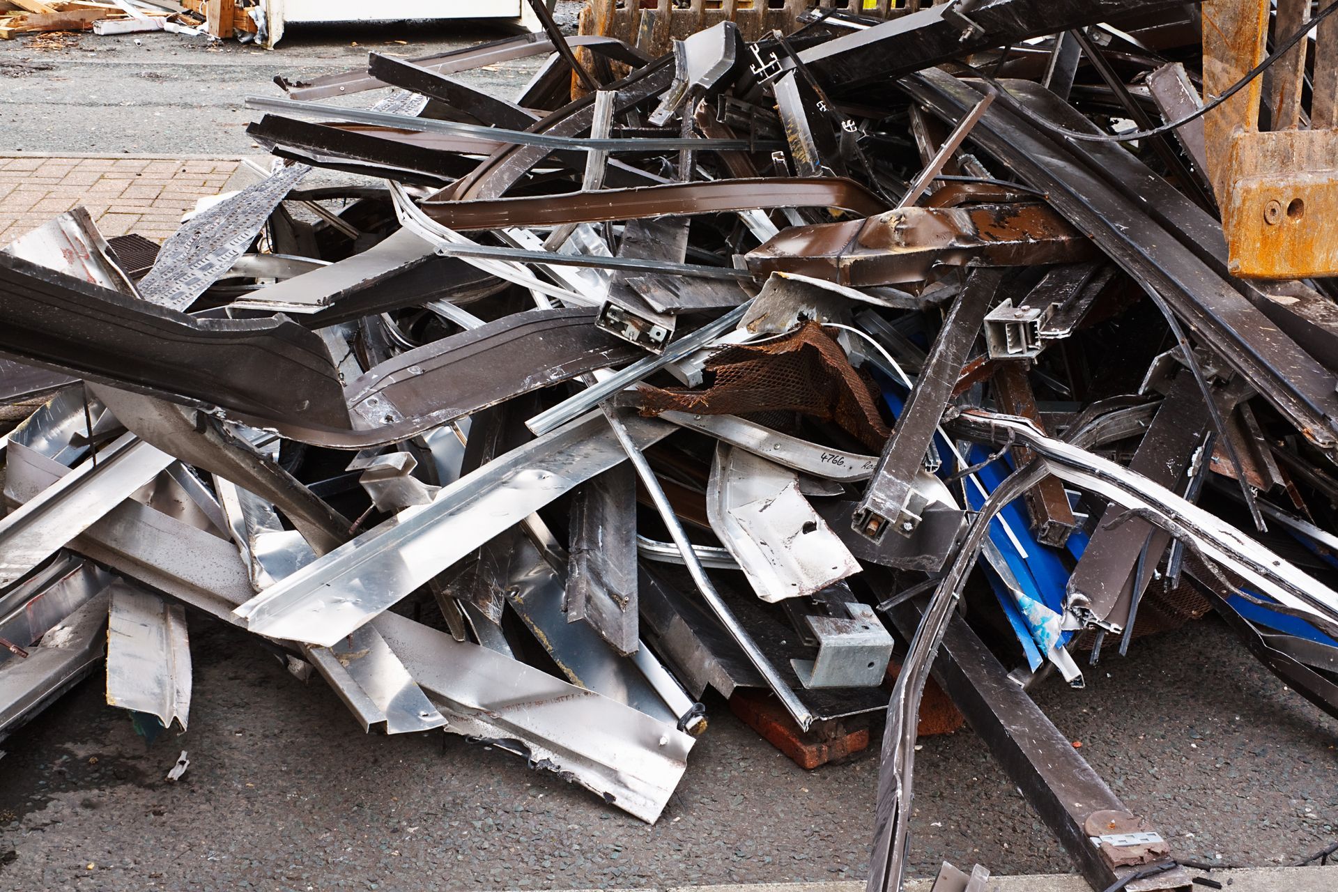 Scrap metal pile on asphalt, containing various metal shapes and pieces; outside. Scrap metal pile on asphalt, containing various metal shapes and pieces; outside.