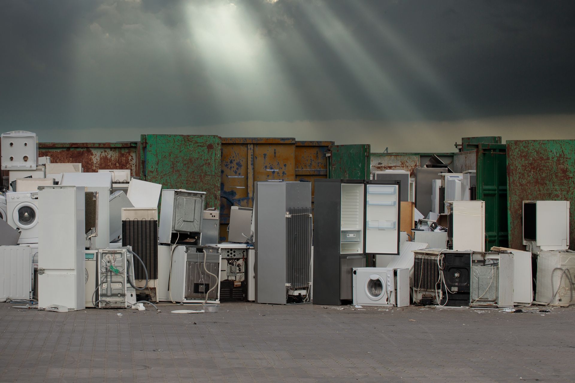 Old appliances in a junkyard under a dark sky with sun rays shining through. Old appliances in a junkyard under a dark sky with sun rays shining through.