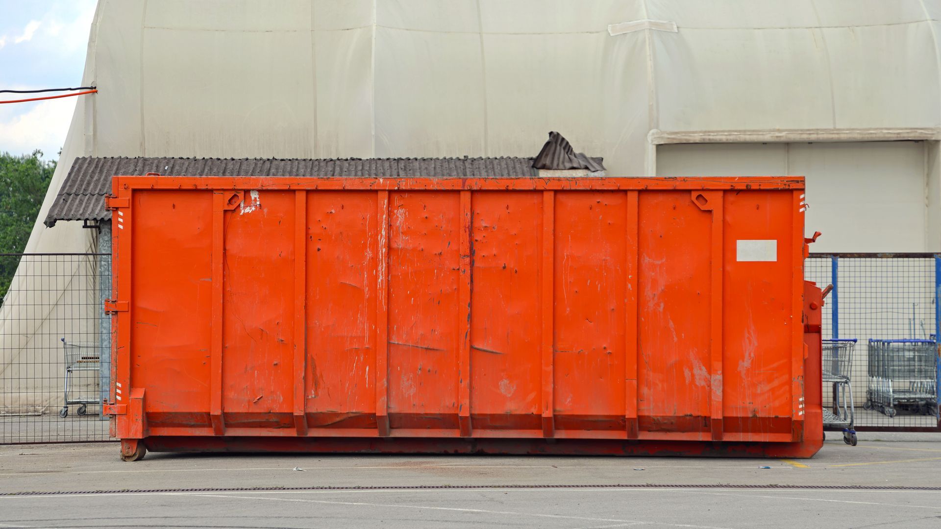 Large orange industrial dumpster in an outdoor construction or industrial area Large orange industrial dumpster in an outdoor construction or industrial area