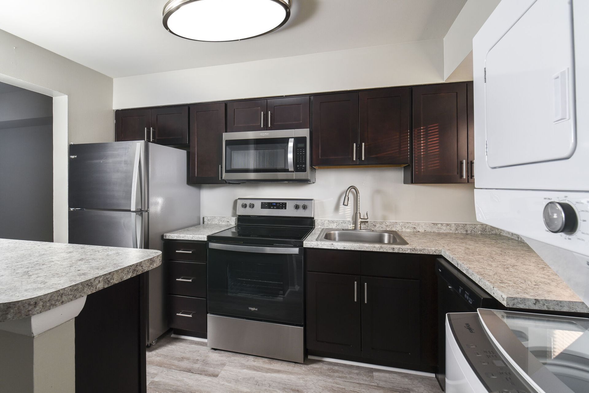 Modern kitchen with dark wood cabinets, stainless steel appliances, and granite counters.
