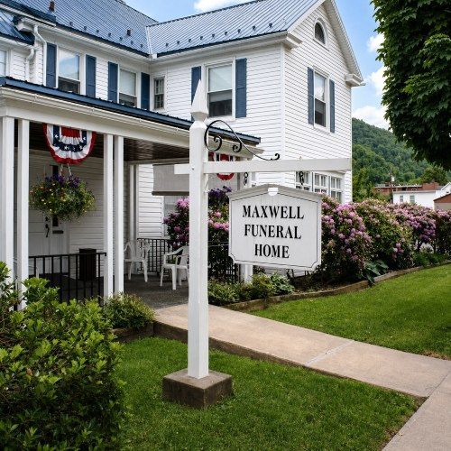 Exterior of funeral home and cremations Renovo, PA with Maxwell Funeral Home sign and white building