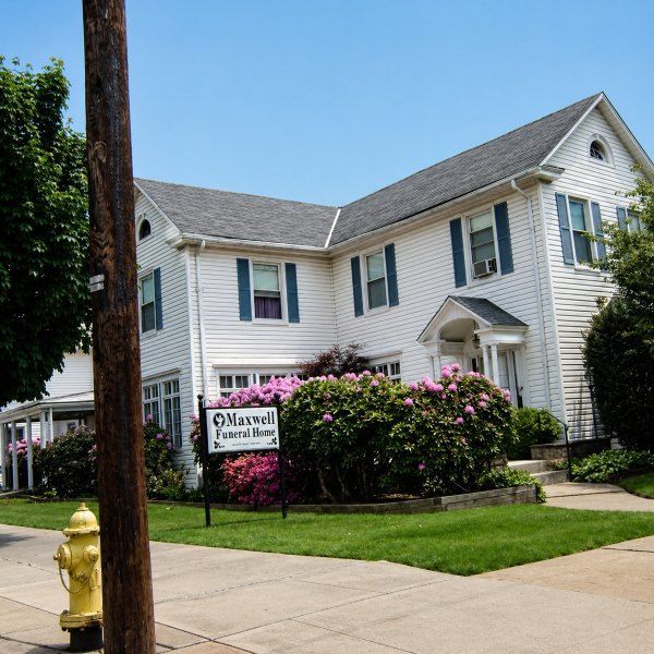 Exterior of Lock Haven, PA funeral home and cremations with Maxwell Funeral Home, lawn, and pink shrubs