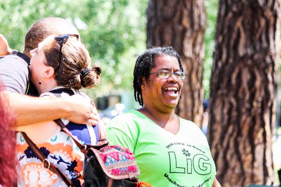 A woman in a green shirt is hugging a man in a park.