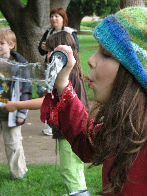 A girl blowing soap bubbles in a park