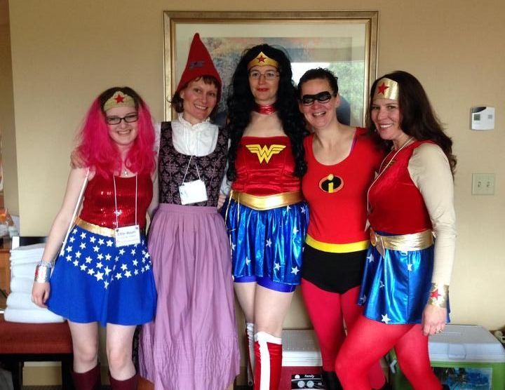 A group of women dressed in superhero costumes pose for a picture