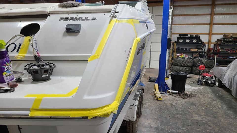 A boat is being painted in a garage with yellow tape.