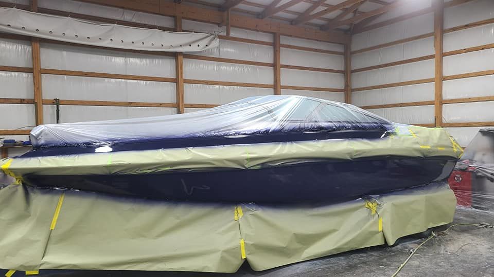 A boat is covered in plastic in a garage.