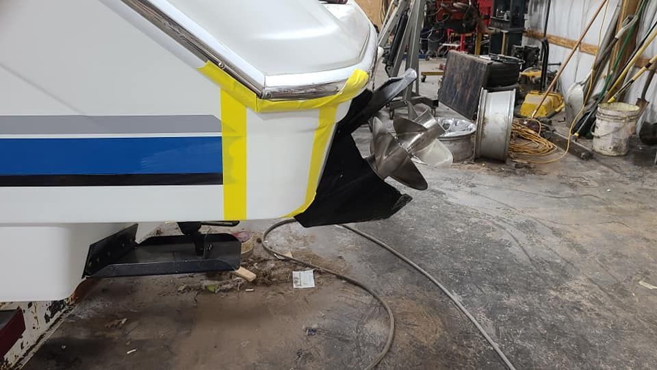 A white and blue boat is sitting in a garage.
