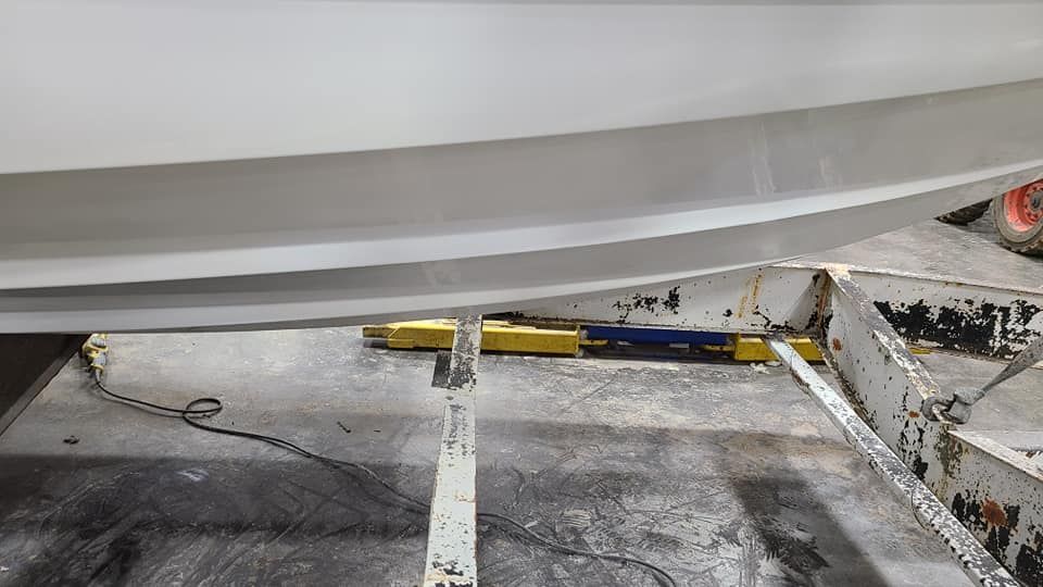 A white boat is sitting on a ramp in a garage.