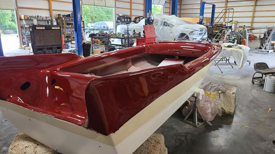 A red boat is sitting on a rock in a garage.