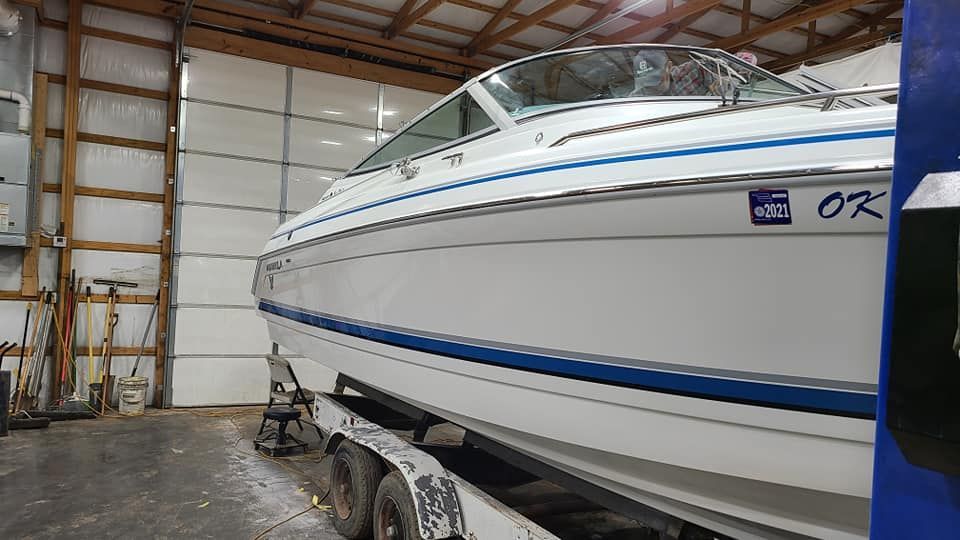 A white boat is sitting on a trailer in a garage.