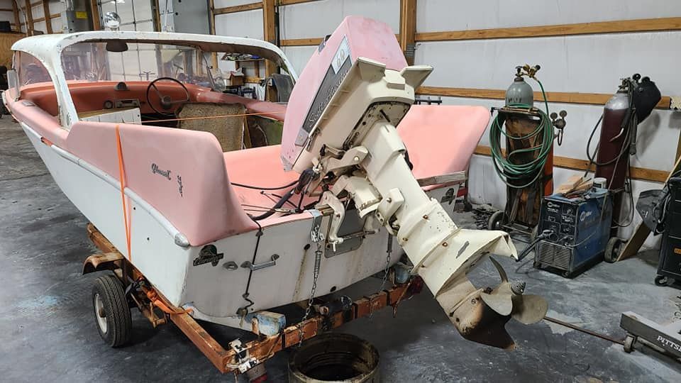 A small boat is sitting on a trailer in a garage.