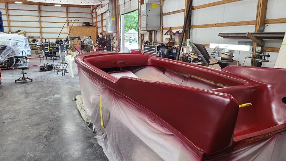 A red boat is being painted in a garage.