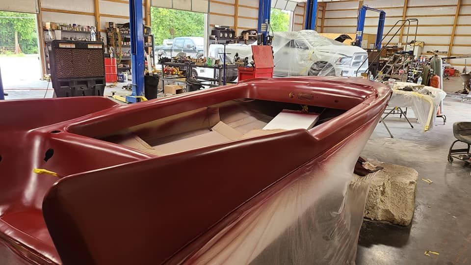 A red boat is sitting in a garage under construction.