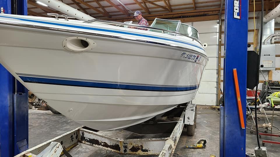 A white boat is sitting on top of a trailer in a garage.