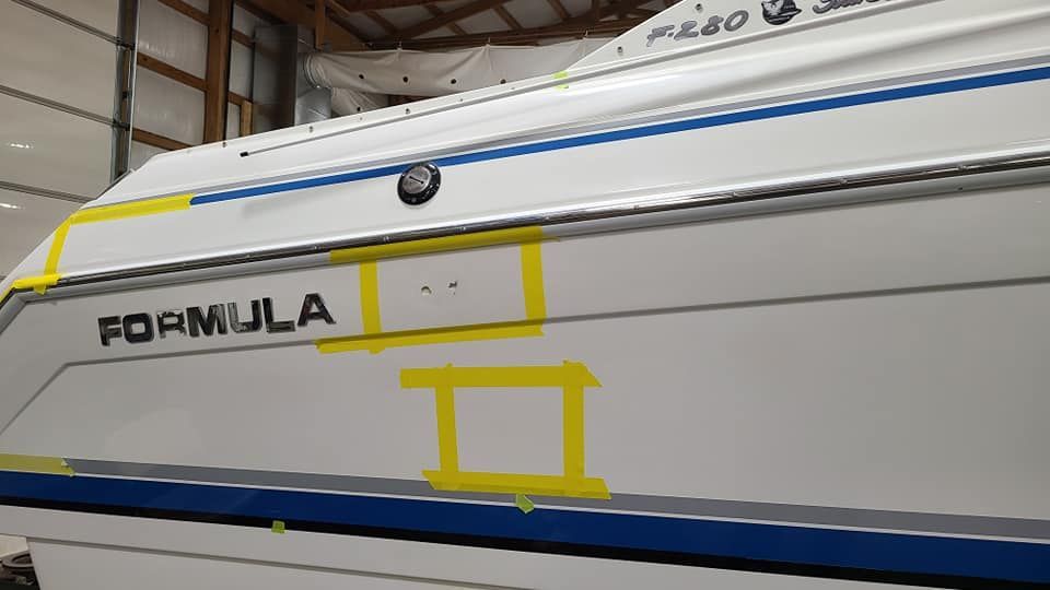 A white boat with formula written on it is sitting in a warehouse.