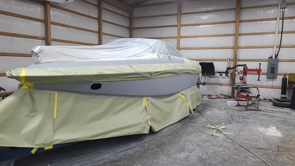 A boat is covered in plastic in a garage.