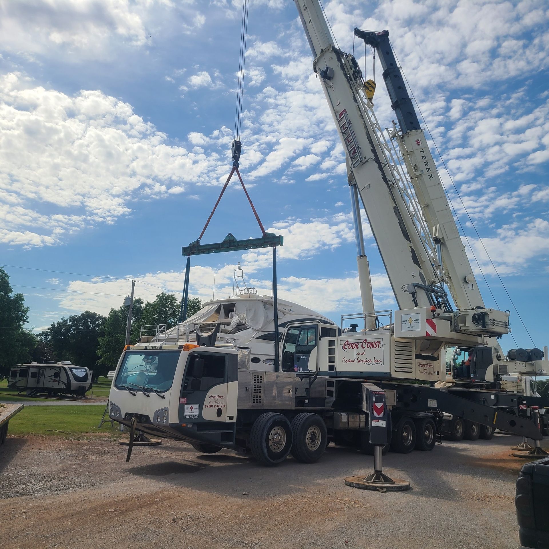 A large crane is lifting a white truck in a parking lot
