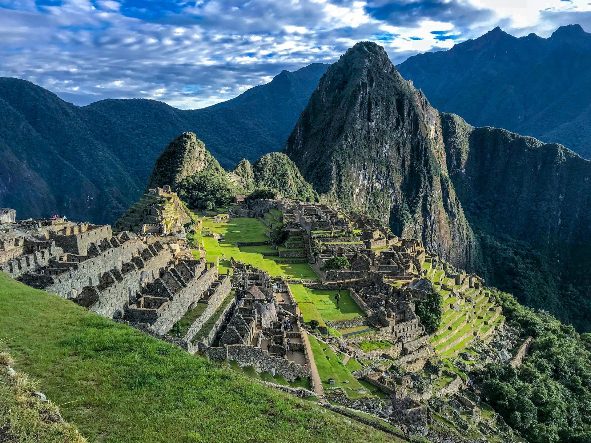 Machu Picchu ruins nestled in green mountains under a cloudy sky.
