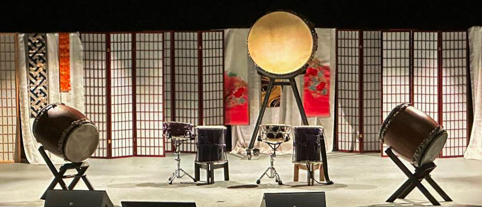 Japanese taiko drums on a stage with a traditional screen backdrop.