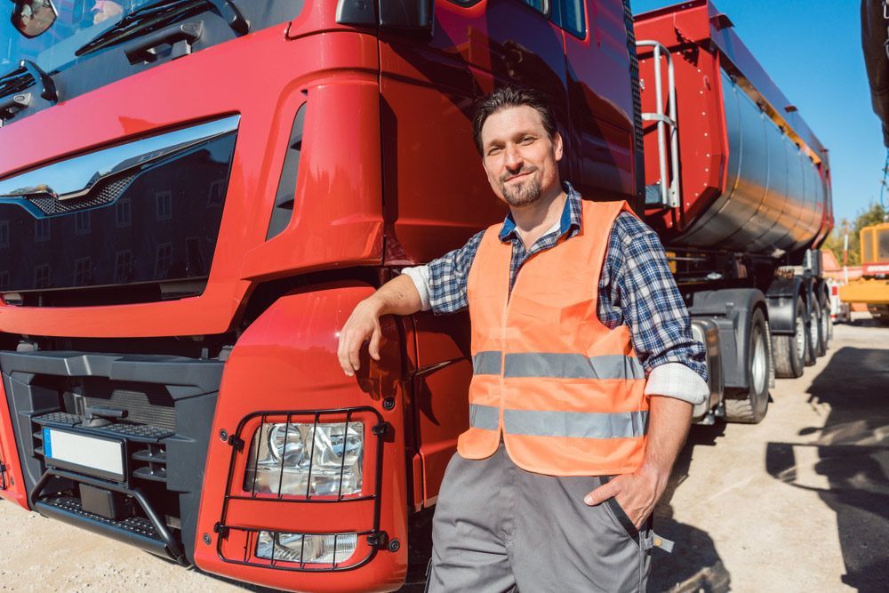 A Man Is Leaning Against A Red Semi Truck — CAL AUTO Mobile Roadworthys in Woodgate, QLD