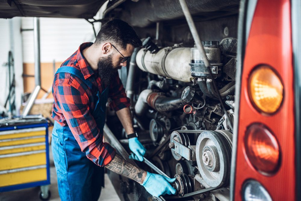 A Man Is Working On The Engine Of A Bus In A Garage — CAL AUTO Mobile Roadworthys in Woodgate, QLD
