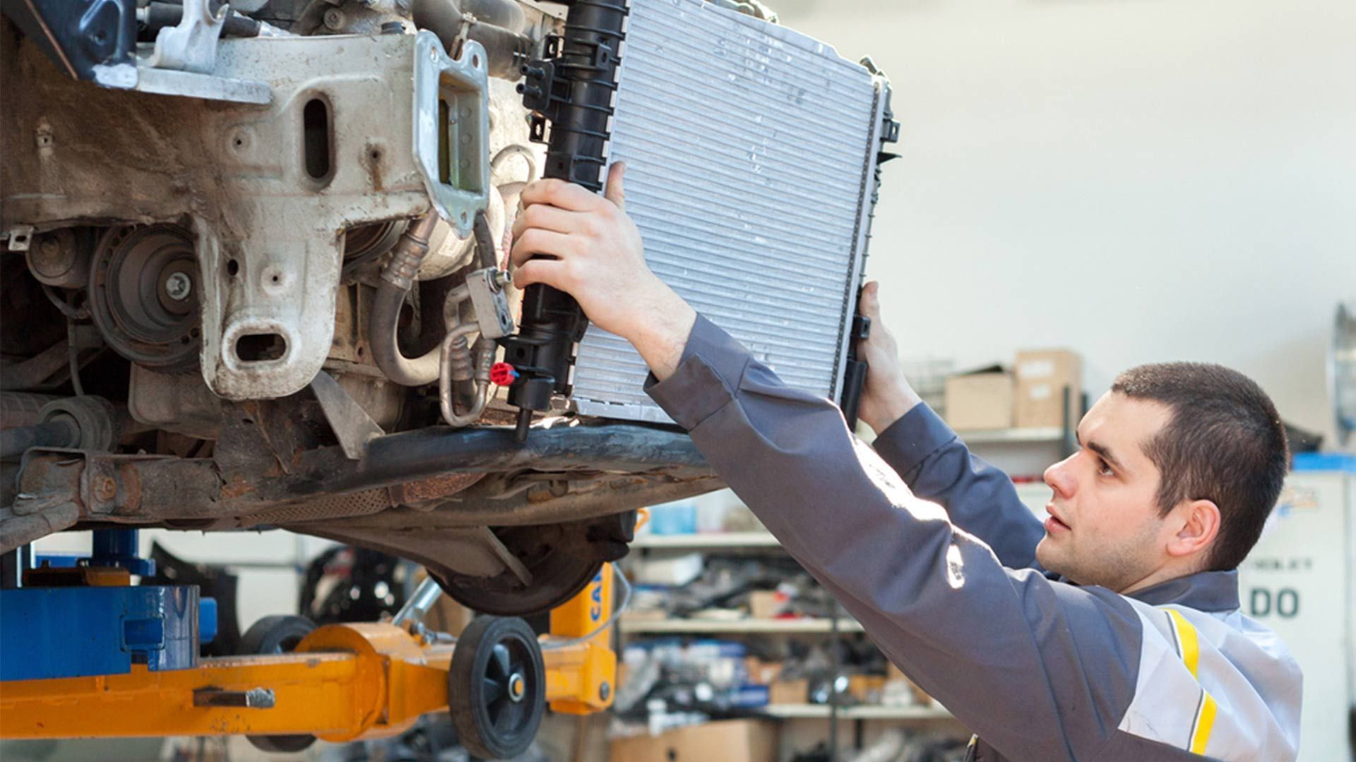 A Man Is Working On A Car Radiator In A Garage — CAL AUTO Mobile Roadworthys in Childers, QLD