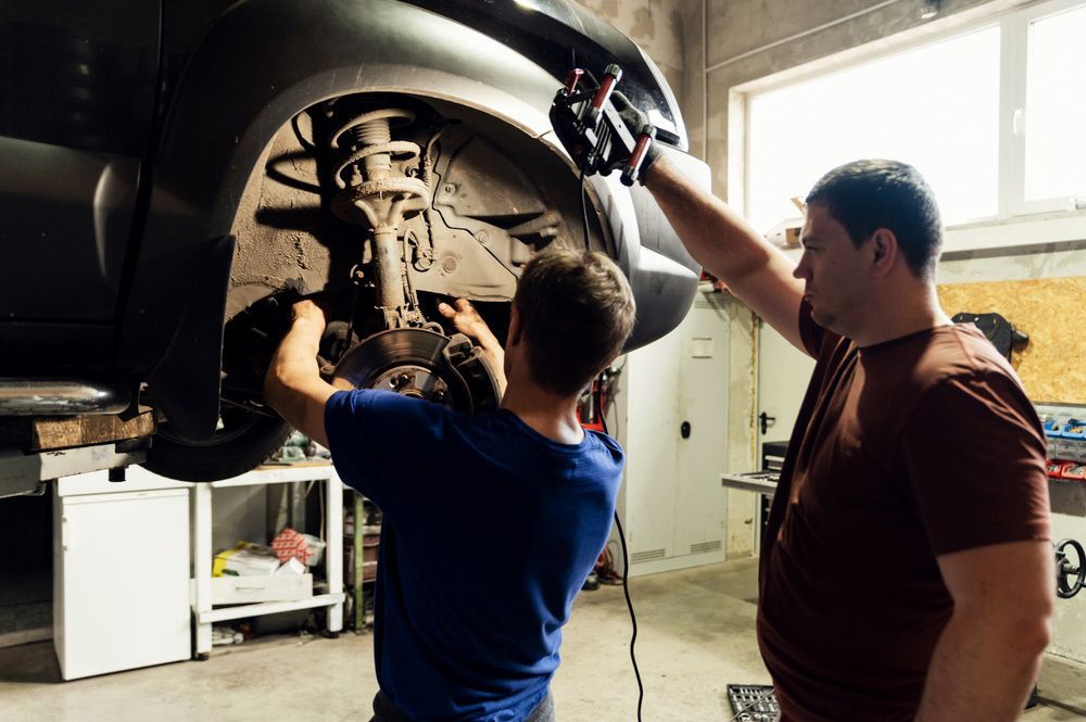 Two Men Are Working On A Car In A Garage — CAL AUTO Mobile Roadworthys in Bargara, QLD