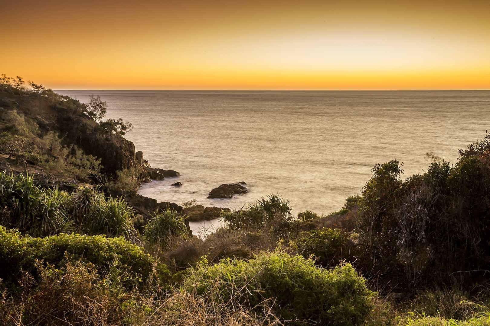 A Sunset Over The Ocean With Trees In The Foreground — CAL AUTO Mobile Roadworthys in Bundaberg, QLD