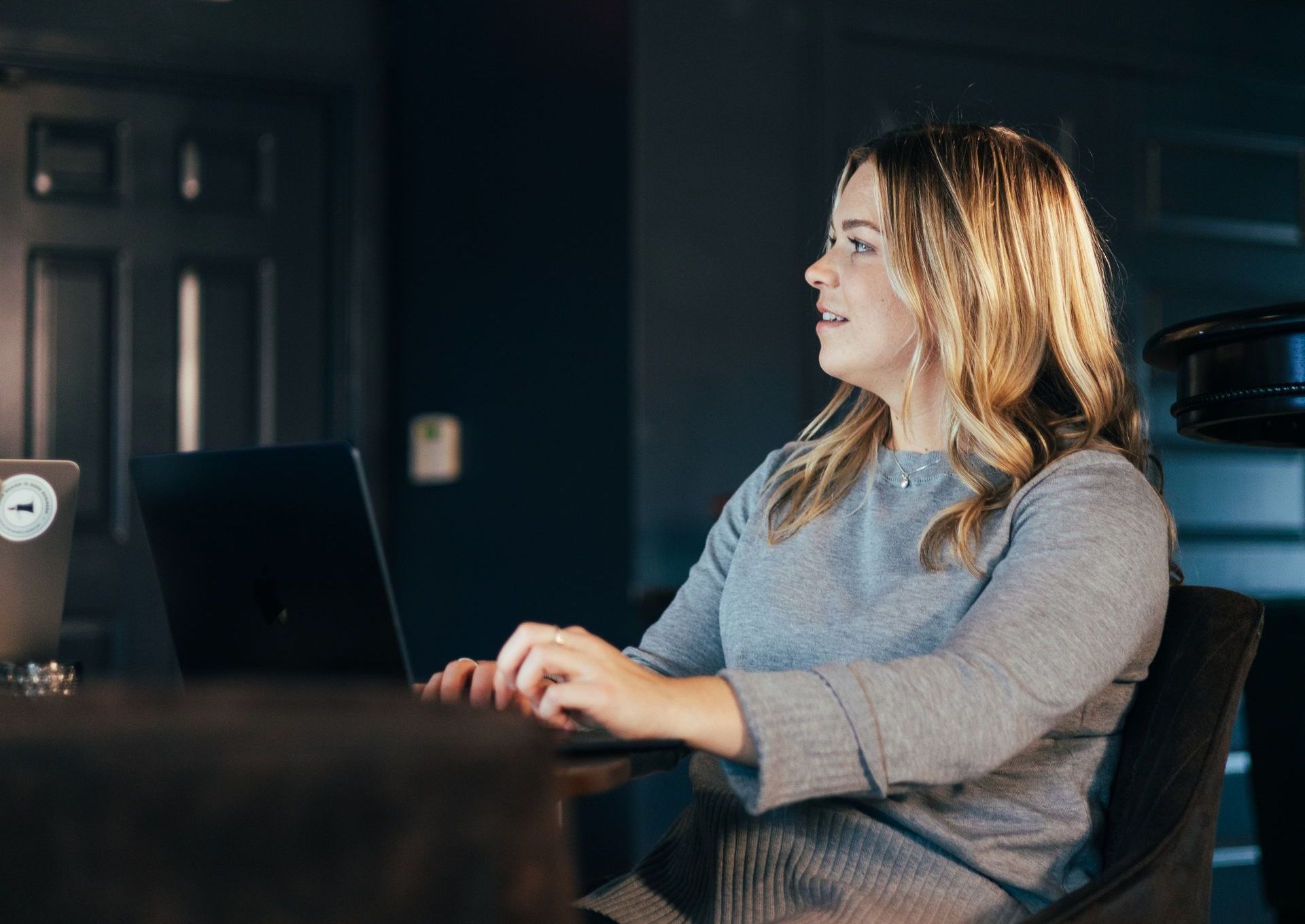 A woman is sitting at a table using a laptop computer.