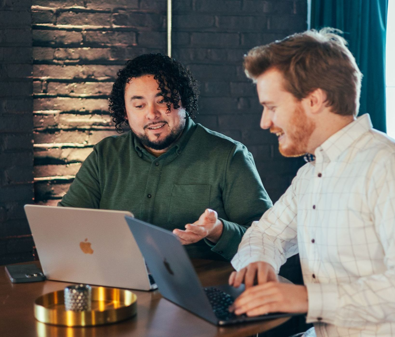 A group of people are sitting around a table with laptops.