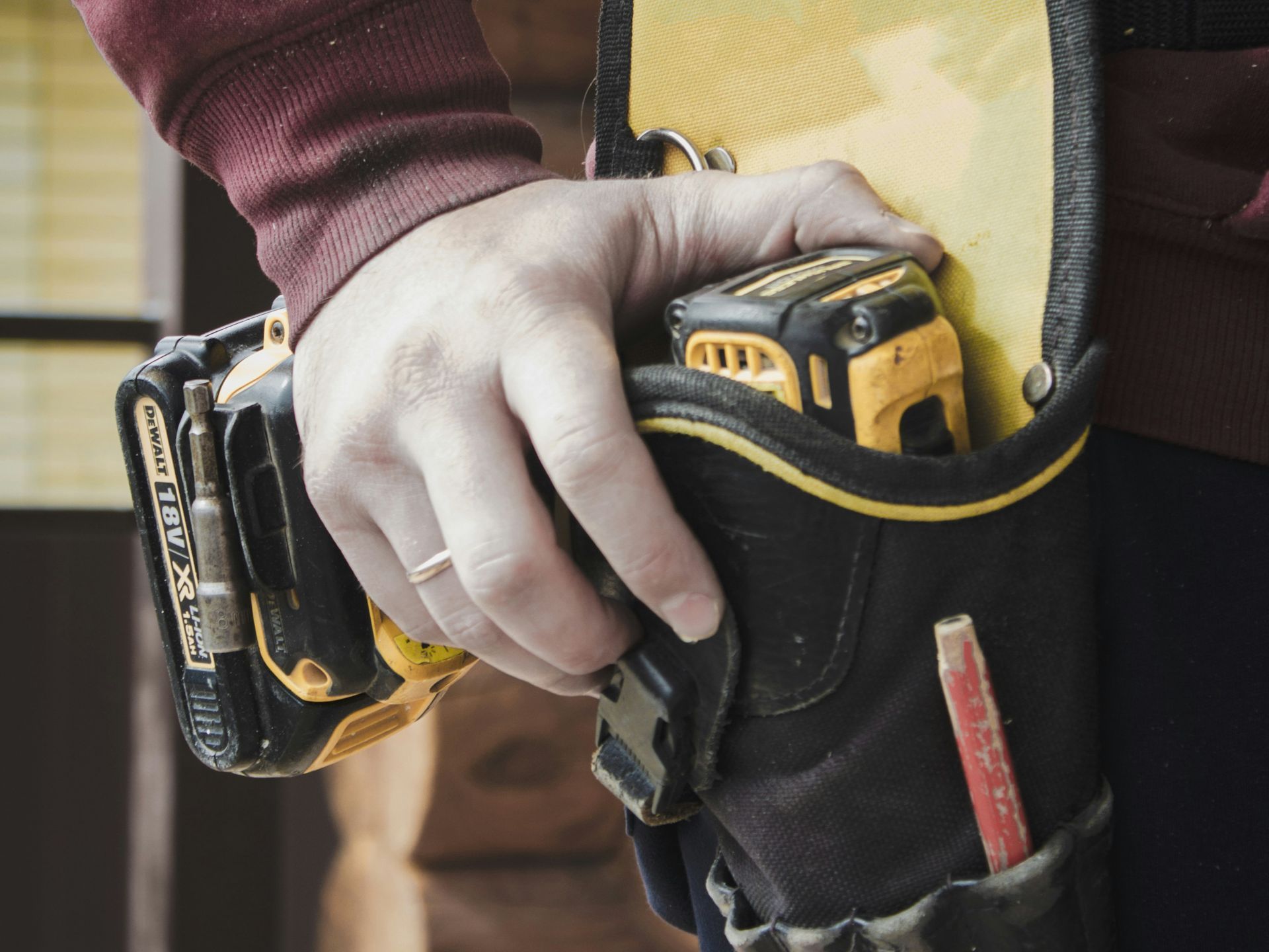 A man is using a grinder to cut a piece of metal on the floor.