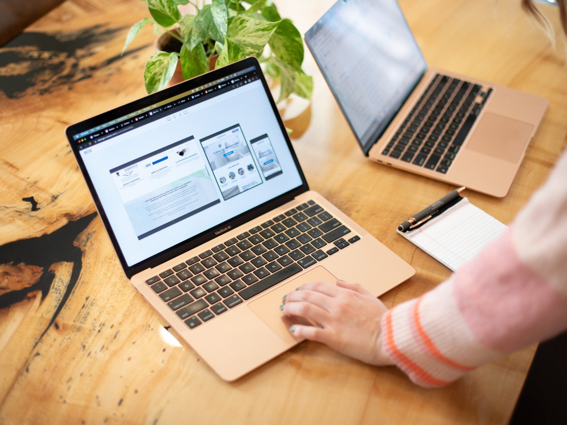 A person is using a laptop computer on a wooden table.