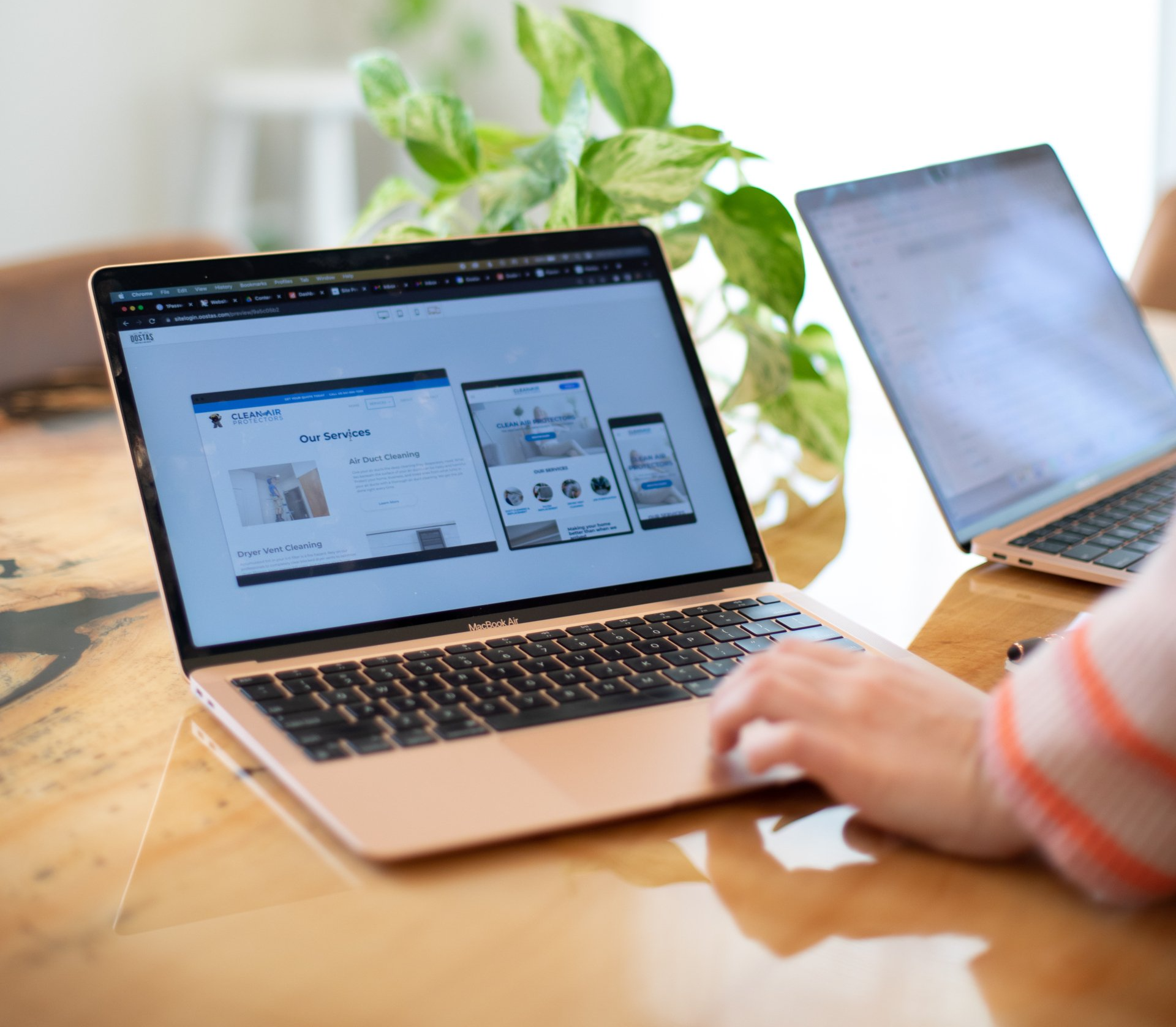 A person is typing on a laptop computer on a wooden table.
