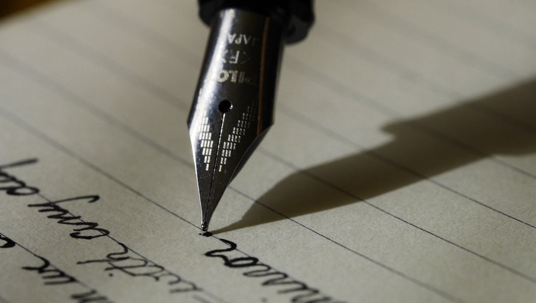 A close up of a fountain pen writing on a piece of paper