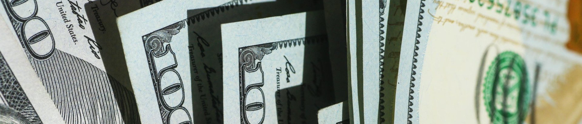 A bunch of dollar bills are stacked on top of each other on a table.