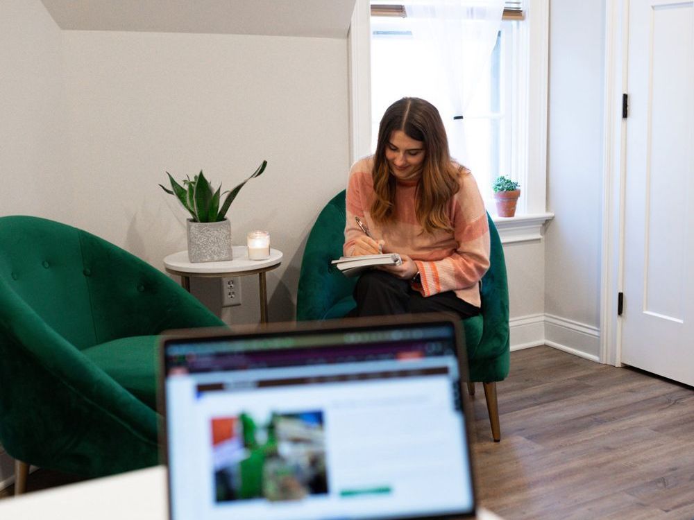 A woman is sitting in a chair in front of a laptop computer.