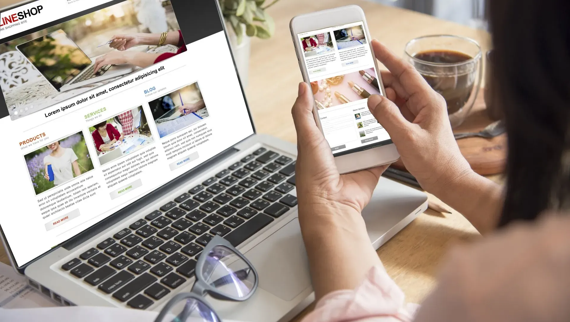 A woman is holding a cell phone in front of a laptop computer.