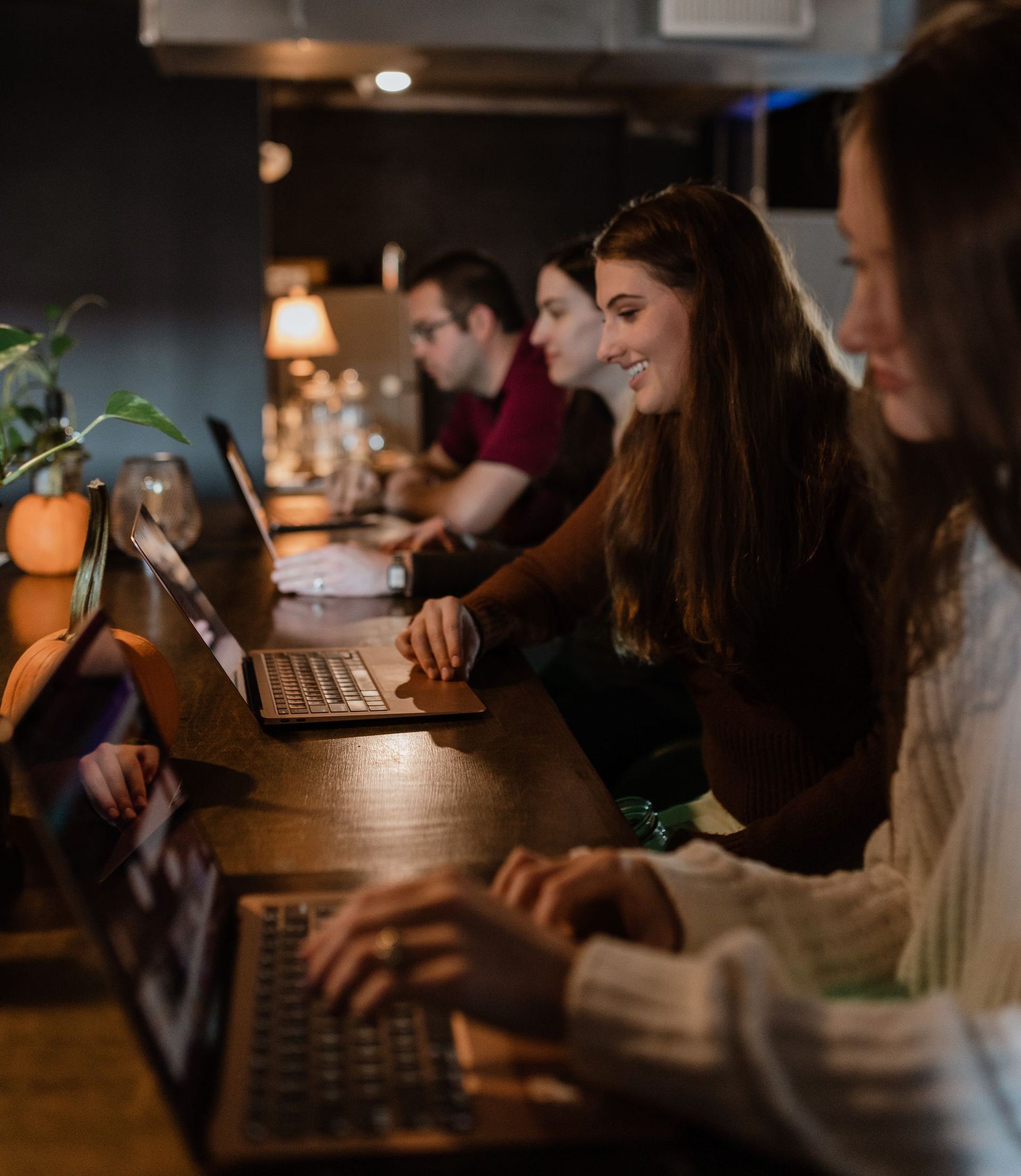 A group of people are sitting at a table using laptops.