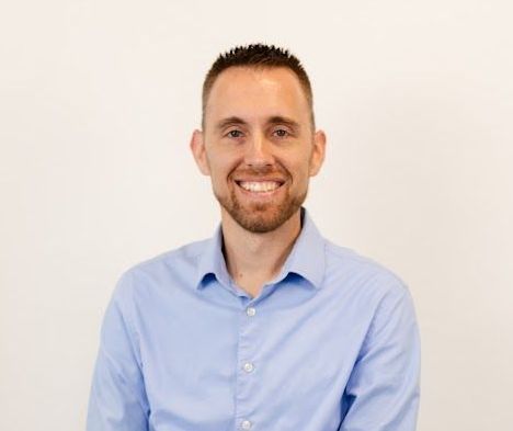 A man in a blue shirt is smiling for the camera.