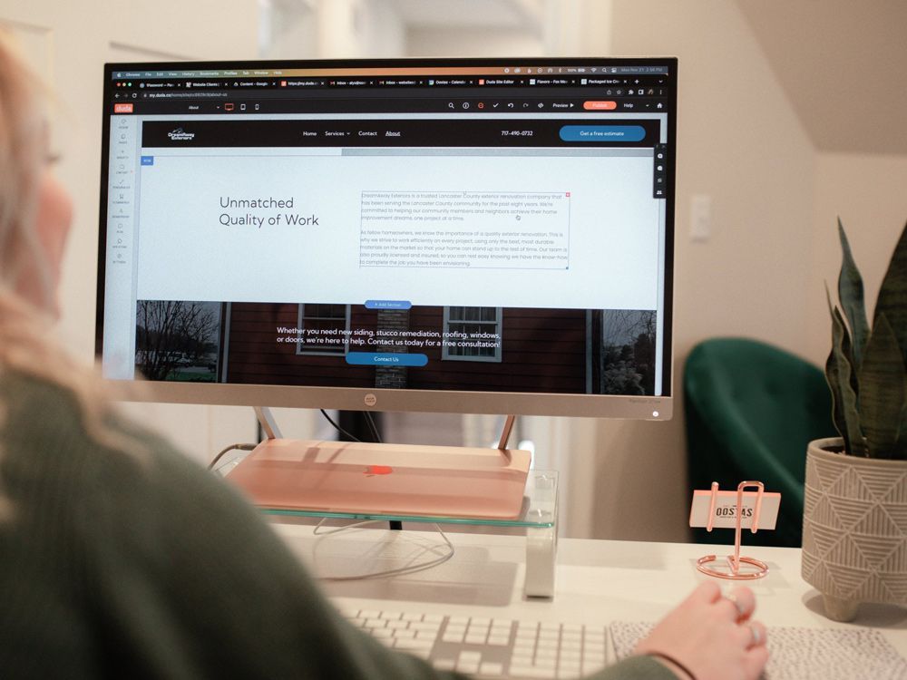 A woman is sitting at a desk looking at a computer screen.