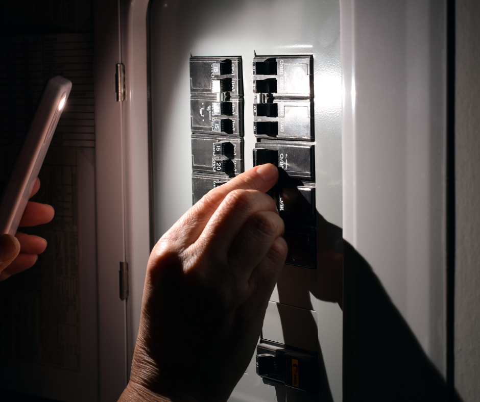 Hand flipping a circuit breaker in a dim electrical panel